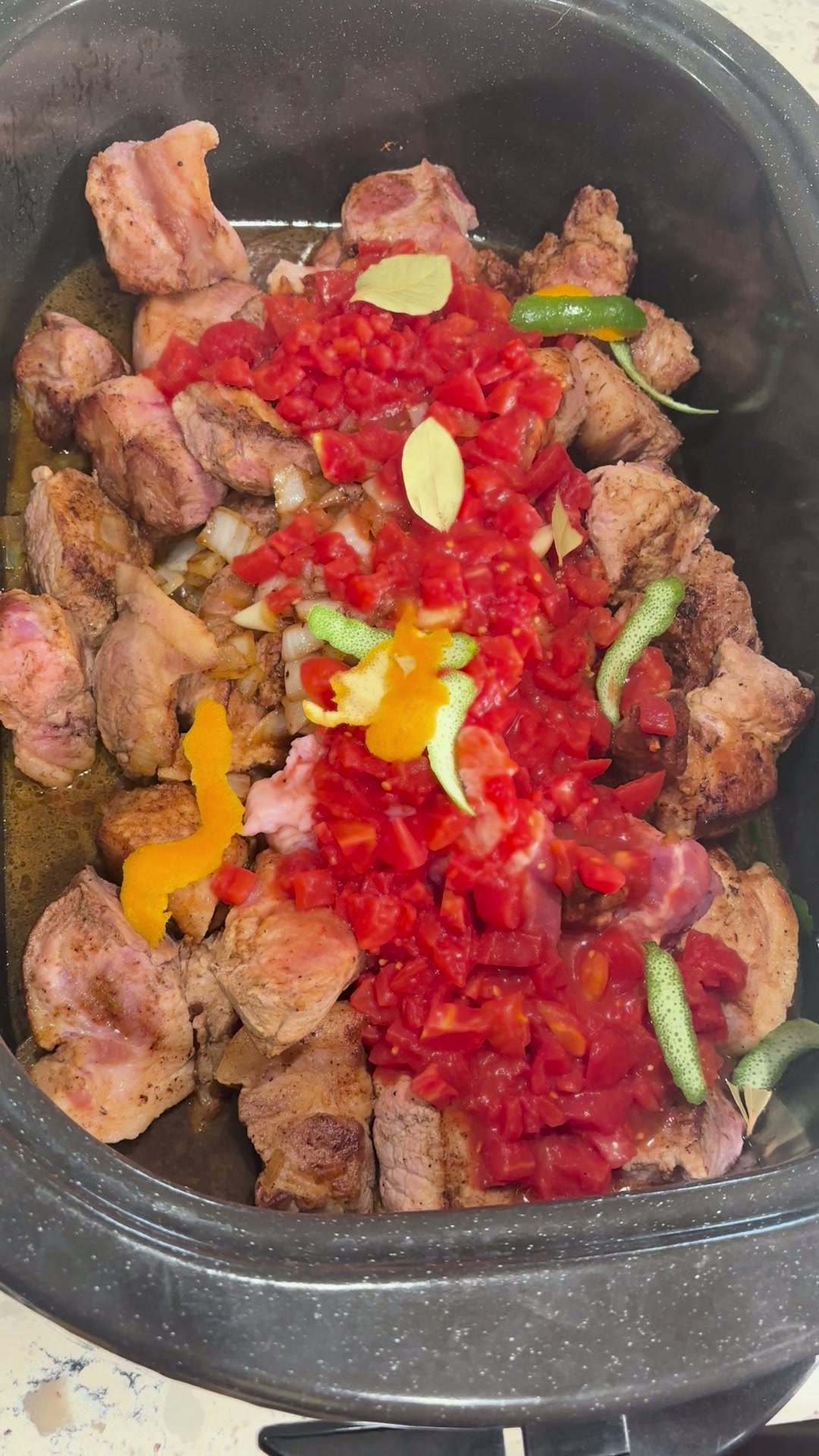 Bay leaves and wide strips of orange and lime zest scattered over the tomatoes